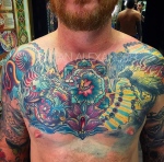 Colorful chest tattoo of a Chinese dragon and ravens with jeweled lotus in color ink by Natan Alexander